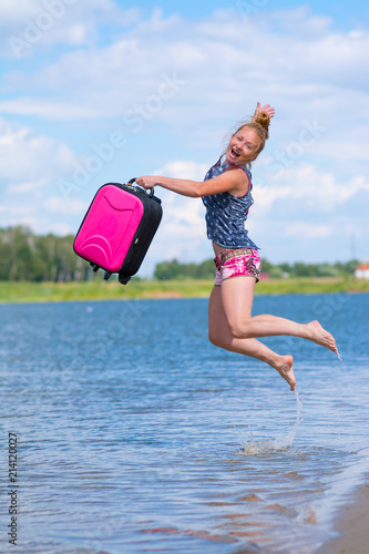 Happy girl jumps into the pond with a suitcase in his hands   © denklim