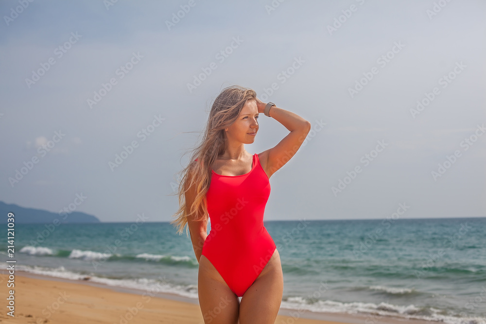 Sexy woman in red swimsuit staying on the beach near ocean, Phuket Sexy woman in red swimsuit staying on the beach near ocean, Phuket