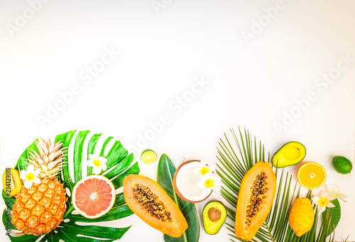 fresh exotic fruits with green tropical leves flat lay top view border, summer diet background, retro toned
