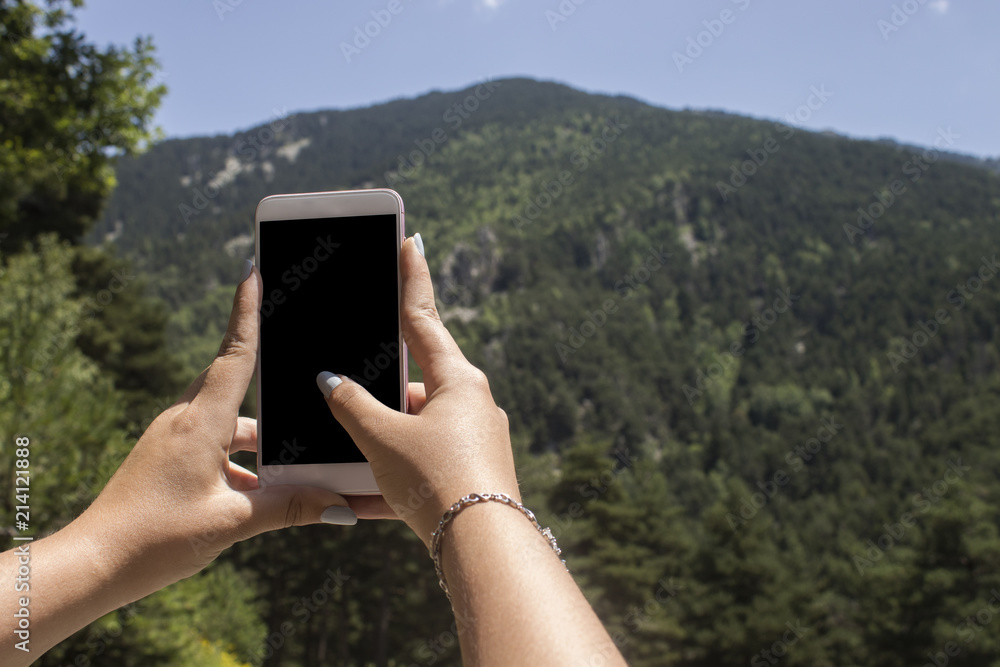 Woman photographing mountain through smartphone