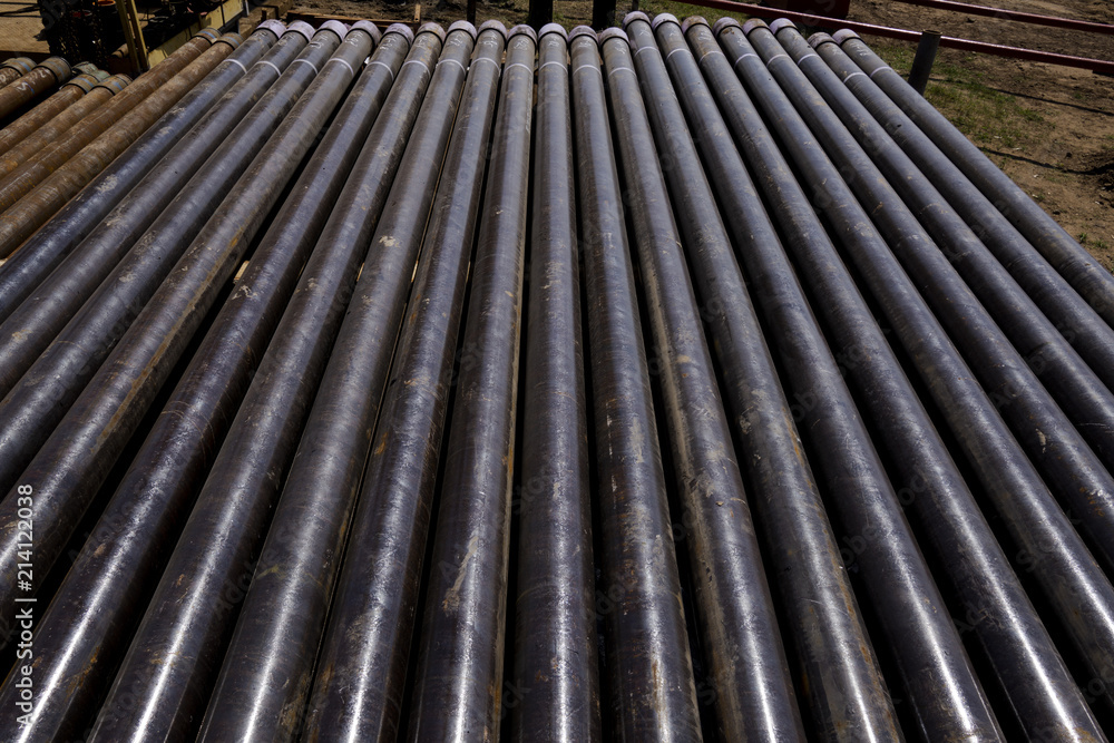 Oil Drill pipe. Rusty drill pipes were drilled in the well section. Downhole drilling rig. Laying the pipe on the deck. View of the shell of drill pipes laid in courtyard of the oil and gas warehouse. Oil Drill pipe. Rusty drill pipes were drilled in the well section. Downhole drilling rig. Laying the pipe on the deck. View of the shell of drill pipes laid in courtyard of the oil and gas warehouse.