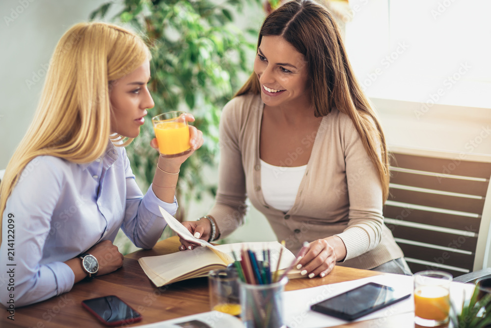 Two students doing homework together and helping each other sitting in a table at home with a homey background Two students doing homework together and helping each other sitting in a table at home with a homey background