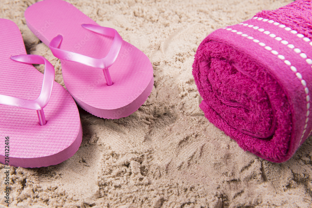 Beach background image of pink flip flops and a beach towel on a sandy ...