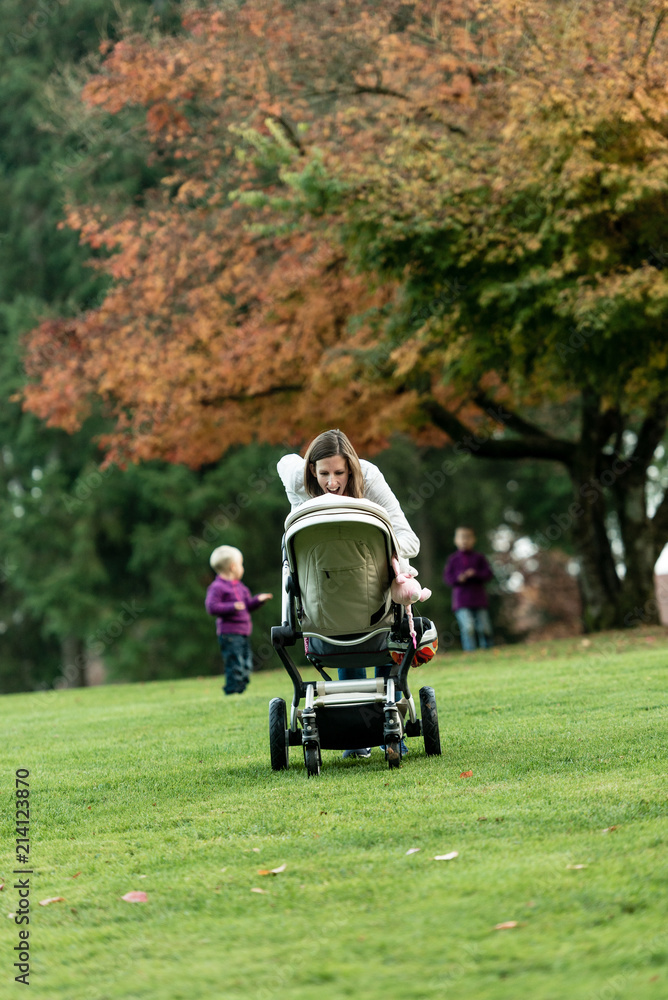 Young mother leaning over a pushchair or stroller Young mother leaning over a pushchair or stroller