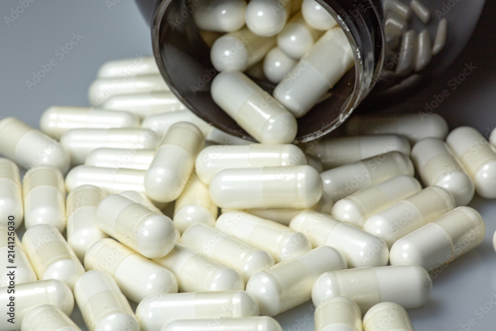 White large pills falling out of a large brown pill bottle White large pills falling out of a large brown pill bottle