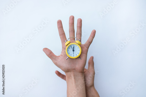 Hand with modern clock, isolated on white background. yellow old style alarm clock, hold in hands