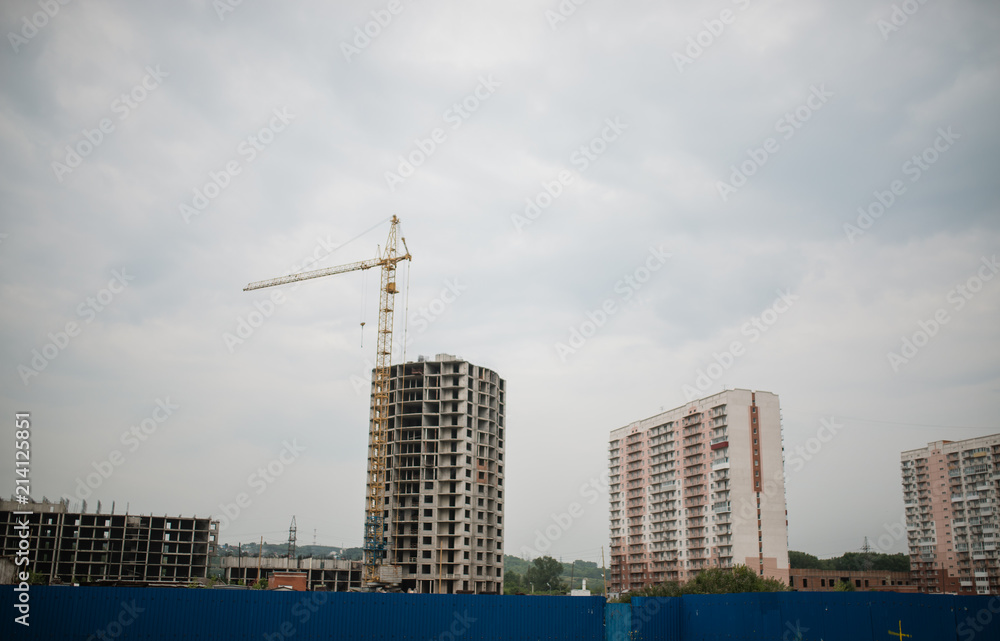 Large crane and construction of building. Inside place for many tall buildings under construction and cranes under a blue sky
