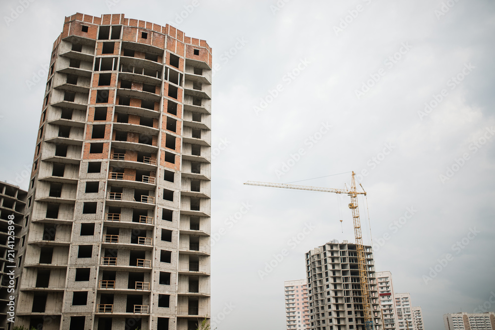 Fototapeta premium Large crane and construction of building. Inside place for many tall buildings under construction and cranes under a blue sky