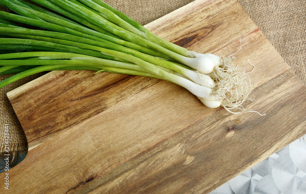scallion,Spring onion or Green onion with root on wooden broad. scallion,Spring onion or Green onion with root on wooden broad.