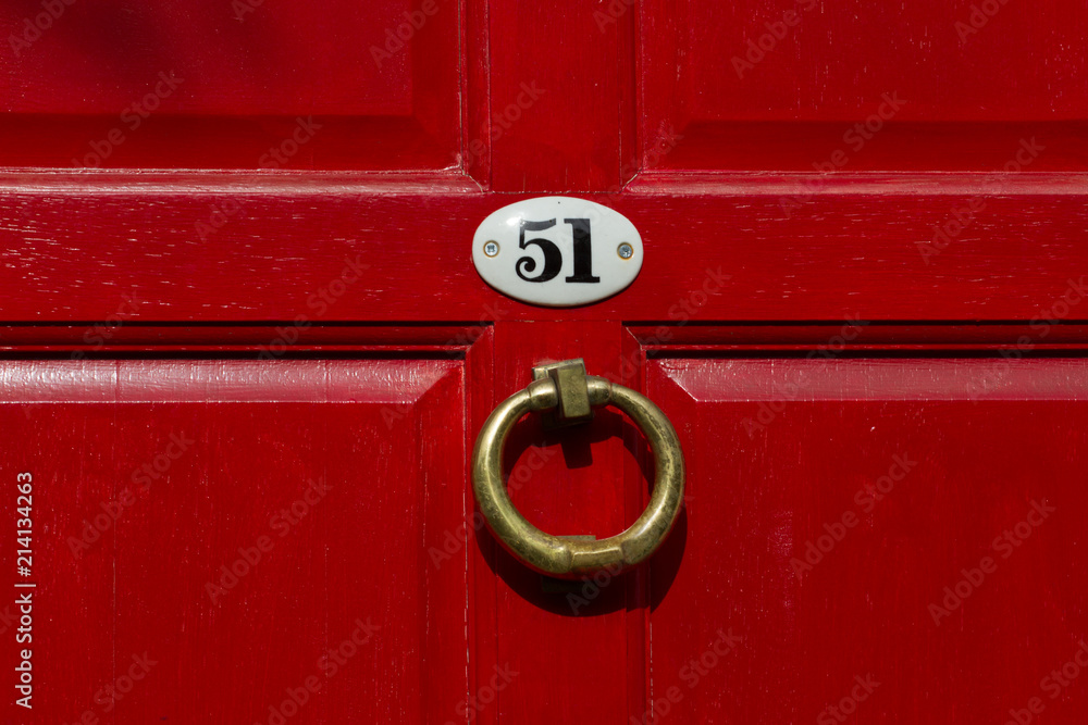 House number fiftyone a red wooden house door with an enamel plaque