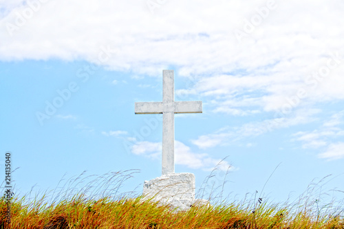 Big christian cross on a field against a blue sky with white clouds