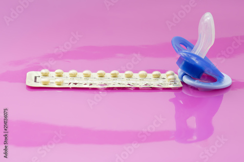 Baby instead of contraception. Blue pacifier and contraceptive pill in front of blister cards of contraceptive pills