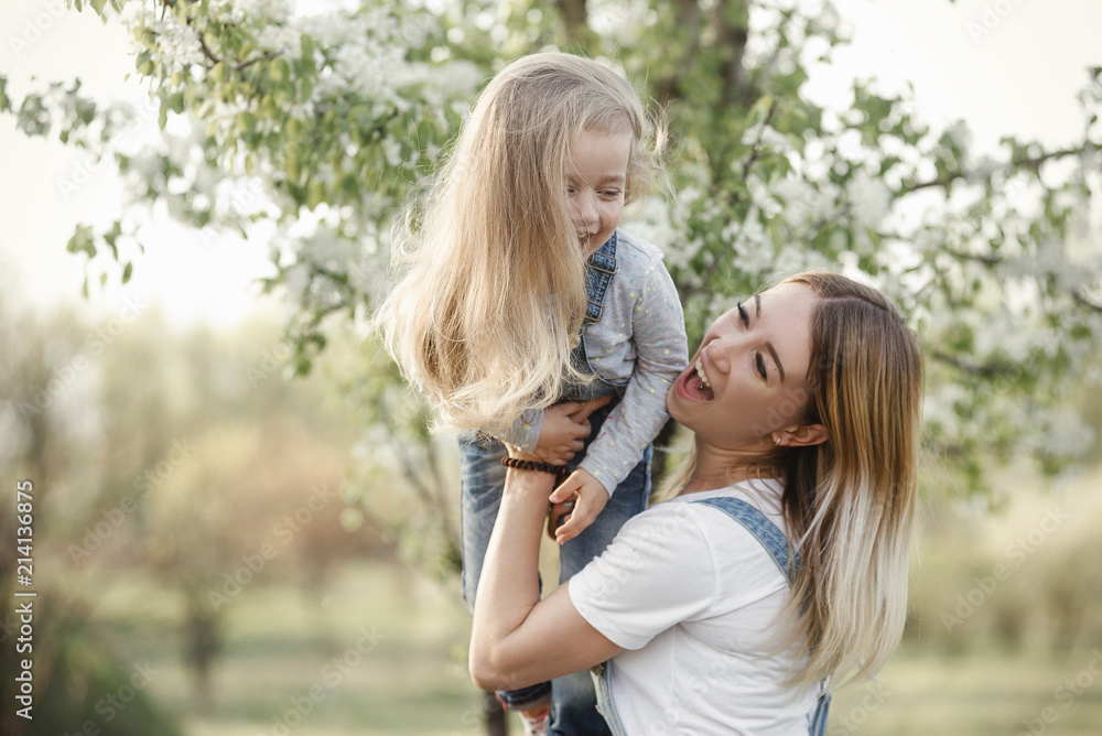 Fototapeta premium young mother with adorable daughter in park with blossom tree