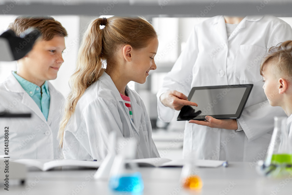 education, science and technology concept - chemistry teacher showing tablet pc computer to kids or students at school laboratory education, science and technology concept - chemistry teacher showing tablet pc computer to kids or students at school laboratory