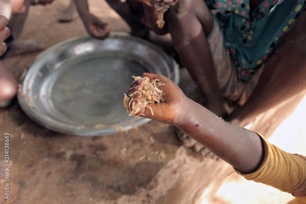 close up of a black kid hand with food inside, with other kids around finishing meal in Africa, outdoos