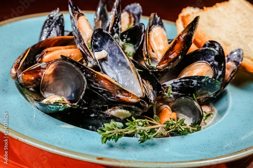 Boiled mussels in copper cooking dish on dark wooden background close up