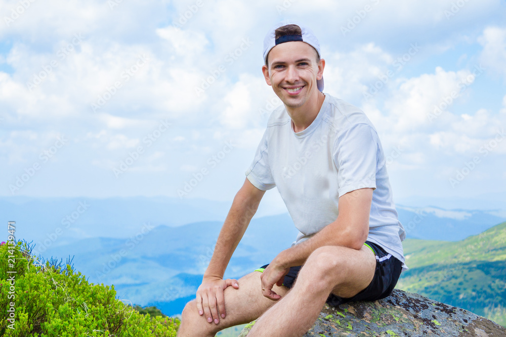 man hiker relaxing on top of hill and admiring beautiful mountain valley view in summer day
