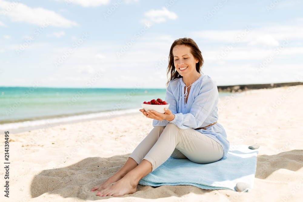 people and leisure concept - happy smiling woman with strawberries on summer beach