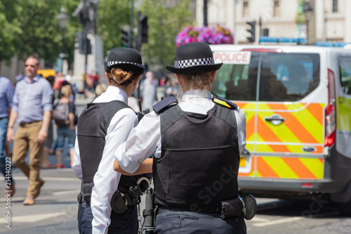 London, England, UK; 13th July 2018; Rear view of Two Female Metropolitan Police Officers in the Street.  Unfoccused Police Van Behind photo