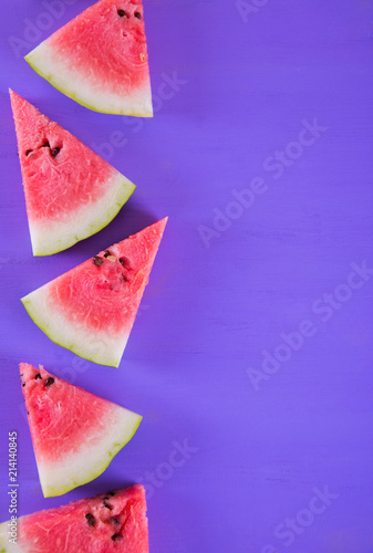 Several slices of fresh watermelon on wooden purple table.