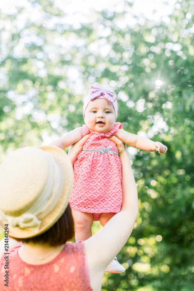 Beautiful Mother with the straw hat And her little daughter outdoors family look in in a pink dress . Young mother throws up baby in the sky, on sunny day. Beautiful Mother with the straw hat And her little daughter outdoors family look in in a pink dress . Young mother throws up baby in the sky, on sunny day.