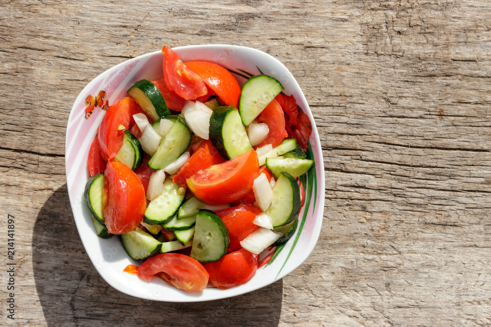 Fresh vegetable salad with tomatoes, cucumbers, onion and olive oil on wooden table. Top view Fresh vegetable salad with tomatoes, cucumbers, onion and olive oil on wooden table. Top view