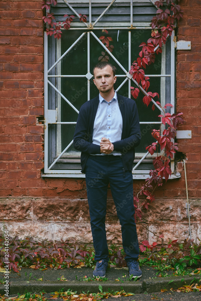 young man stands on the street near brick house. Architecture, nature, outdoors young man stands on the street near brick house. Architecture, nature, outdoors
