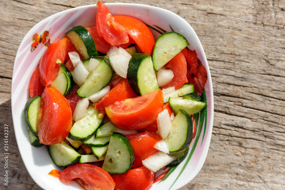 Fresh vegetable salad with tomatoes, cucumbers, onion and olive oil on wooden table. Top view Fresh vegetable salad with tomatoes, cucumbers, onion and olive oil on wooden table. Top view