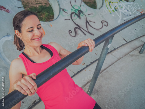 fit and sporty woman in pink sportswear does pull-ups as workout outside in the park  photo