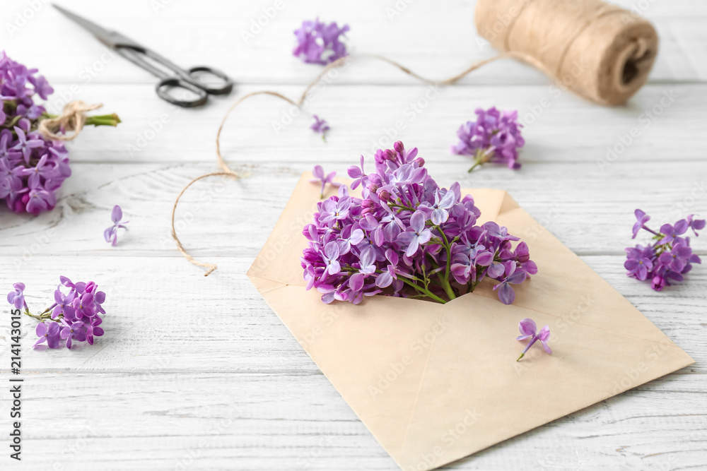 Envelope and beautiful blossoming lilac on table. Spring flowers Envelope and beautiful blossoming lilac on table. Spring flowers
