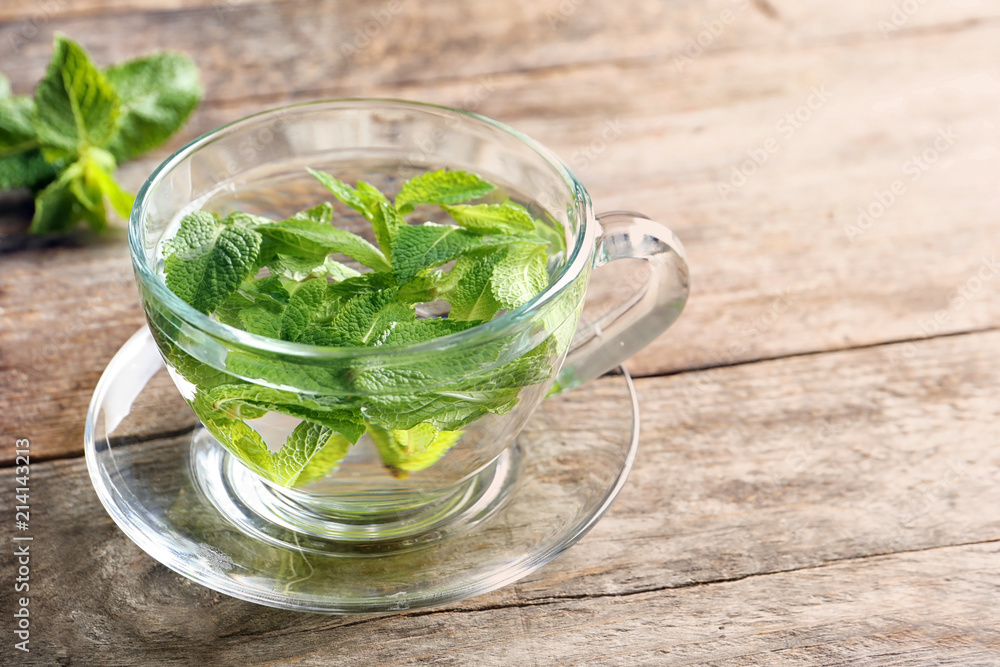 Cup with hot aromatic mint tea on wooden table Cup with hot aromatic mint tea on wooden table