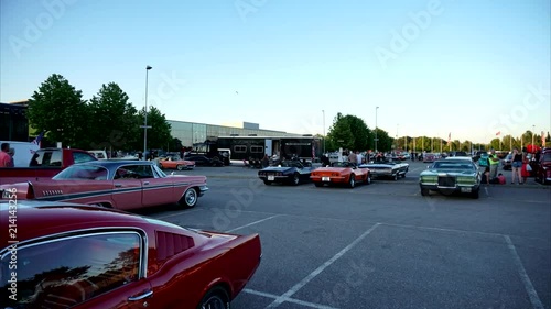 Timelapse at parking spot with old american classic muscle cars with people around.