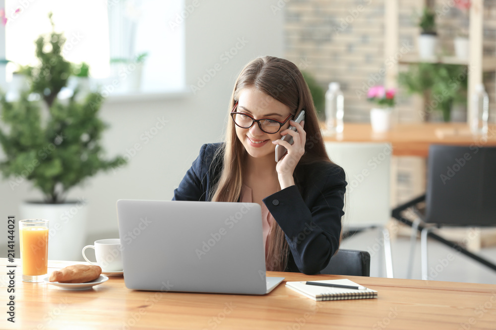 Female freelancer talking by phone while working on laptop in cafe Female freelancer talking by phone while working on laptop in cafe