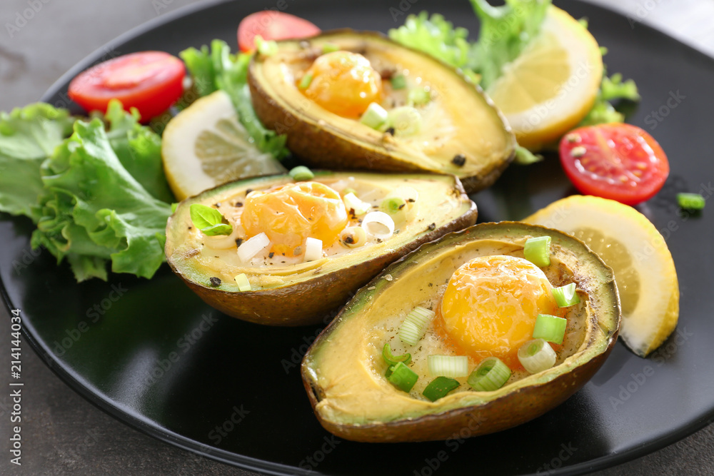Eggs baked in avocado and fresh vegetables on plate, closeup Eggs baked in avocado and fresh vegetables on plate, closeup