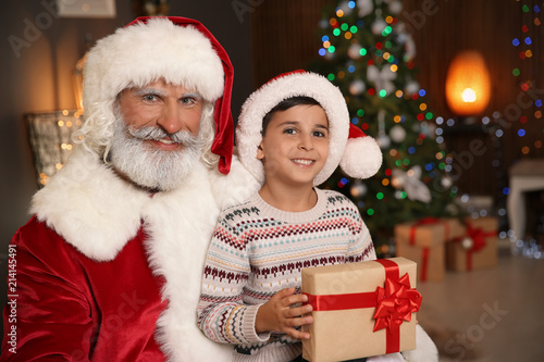 Little child with Santa Claus and Christmas gift at home