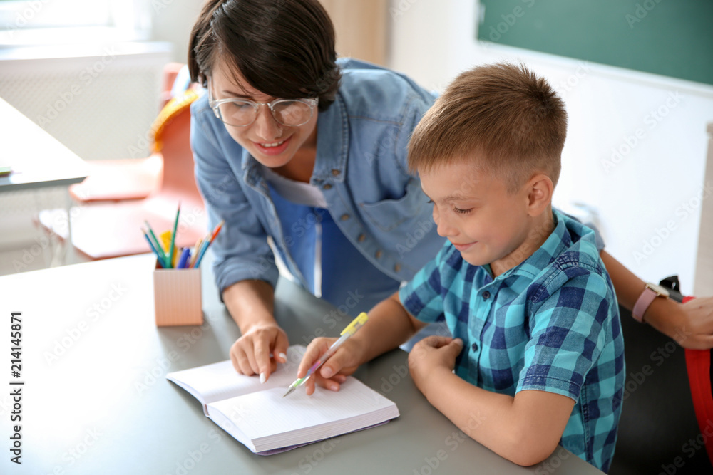 Female teacher helping child with assignment at school Female teacher helping child with assignment at school