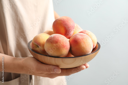 Woman holding plate with fresh sweet peaches, closeup