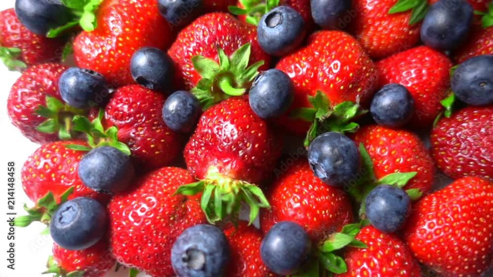 Red ripe garden strawberry and blueberry, rotation of berries on white table, beautiful background Red ripe garden strawberry and blueberry, rotation of berries on white table, beautiful background