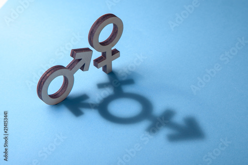 Fotografie Symbols of man and woman cast shadow in the form of transgender on blue