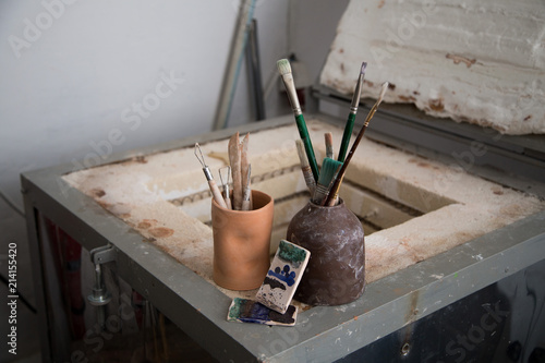 Pottery loops ans fettling knives, brushes and glase samples on a pottery oven kiln. photo