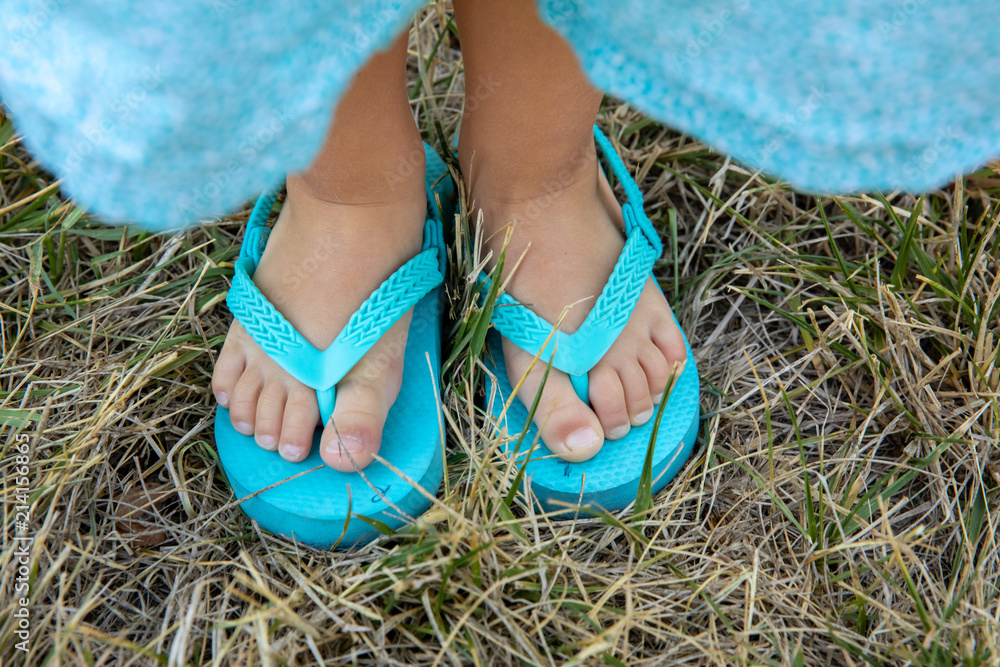 A Little Girl's Feet in Turquoise Flip Flops With R and L printed on ...