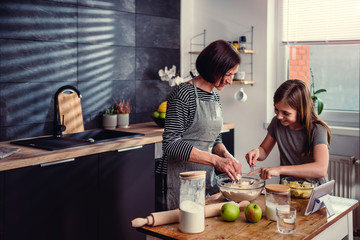 Mother and daughter making dough for apple pie