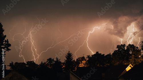 Thunderbolt over the houses and dark stormy sky on the yellow background (grunge overlay)