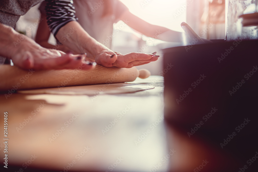 Mother and daughter rolling dough on wooden table Mother and daughter rolling dough on wooden table