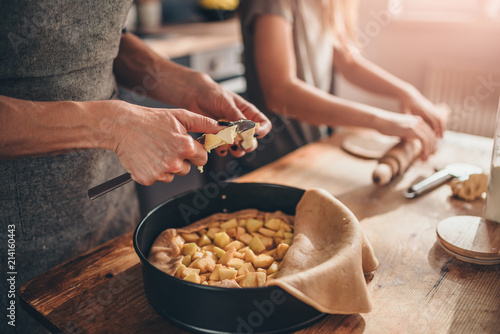 Woman cutting butter into apple pie photo