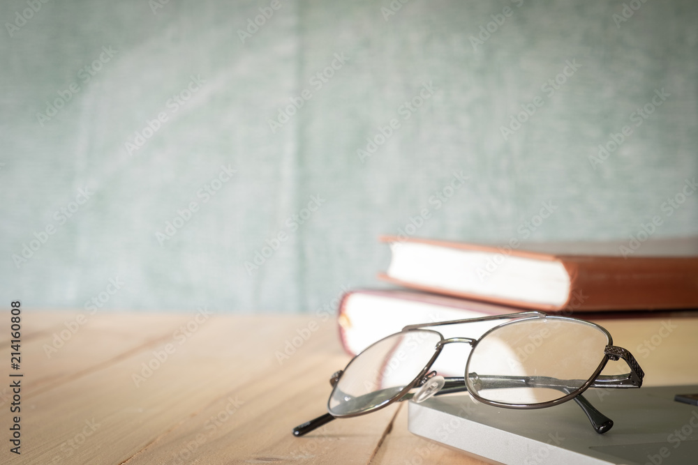 Eyeglasses and books on chalkboard background Eyeglasses and books on chalkboard background