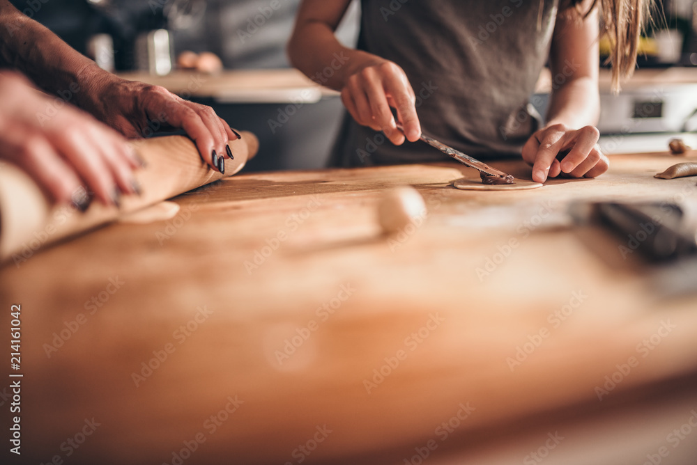 Mother and daughter filling ravioli with chocolate cream Mother and daughter filling ravioli with chocolate cream