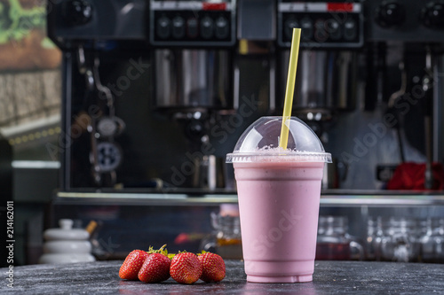 Strawberry milk shake to take away with straw on a dark background