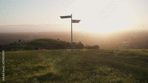 Man walking down walking trail at sunset with street sign on hill