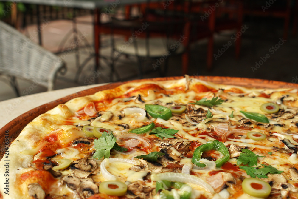 Vegetarian pizza with onions, pepers olives and cheese, restaurant atmosphere